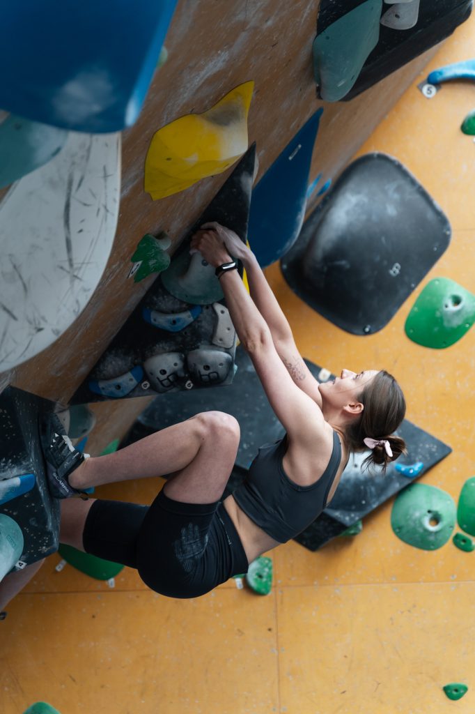 Młoda kobieta wspina się na ściance wspinaczkowej